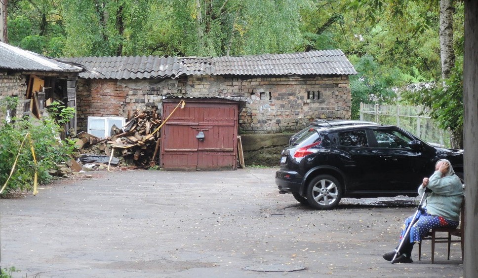 Una anciana a la entrada de un patio interior que alberga un aarboleda